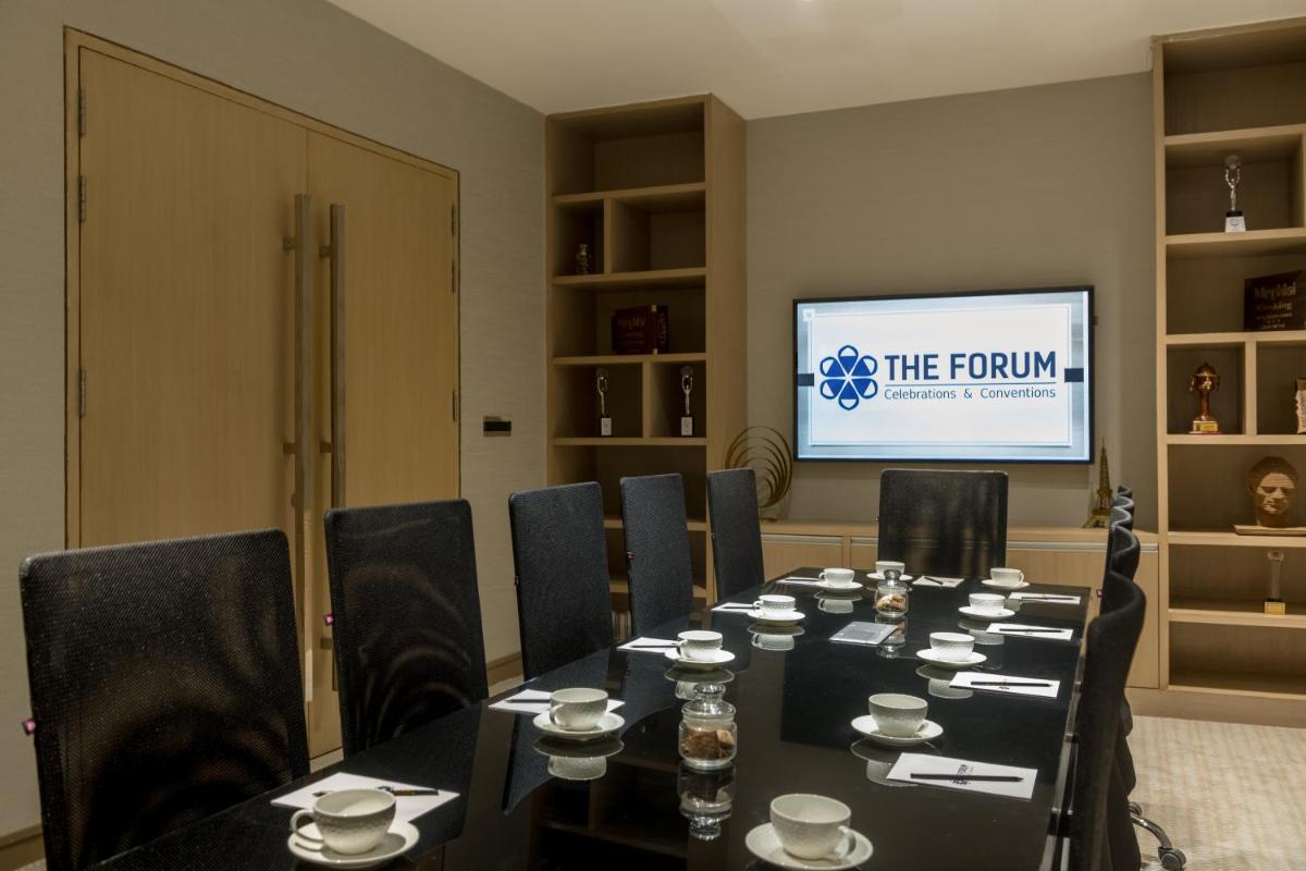 a conference room with a table and chairs and a screen at Wyndham Ahmedabad Shela in Ahmedabad