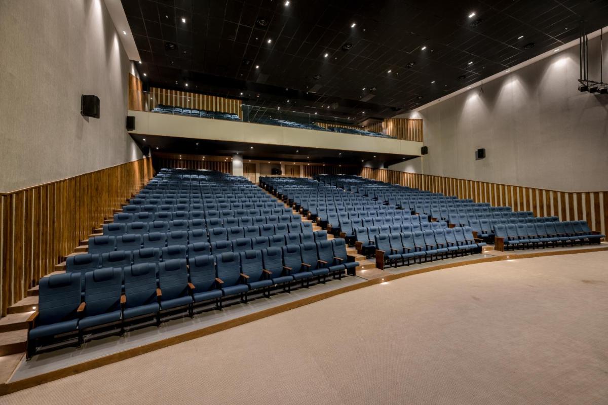 an empty auditorium with blue seats in a theatre at Wyndham Ahmedabad Shela in Ahmedabad