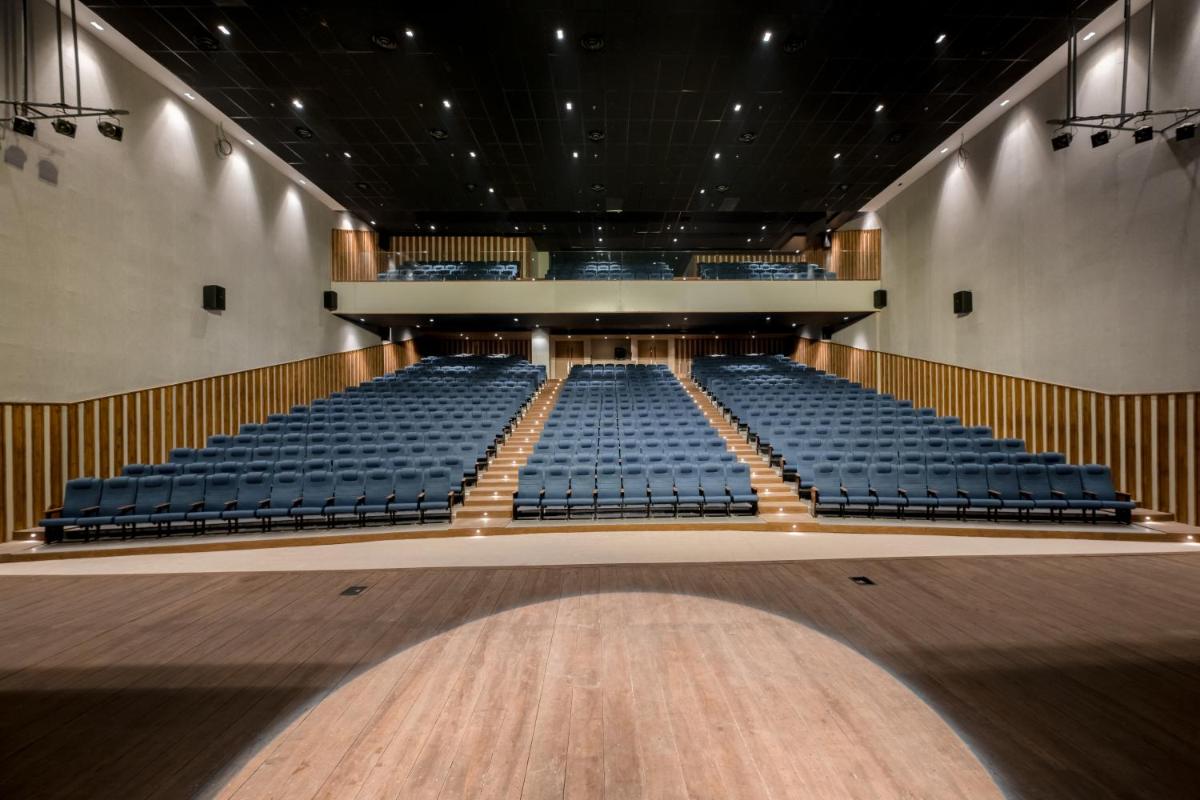 an empty auditorium with blue seats and a stage at Wyndham Ahmedabad Shela in Ahmedabad