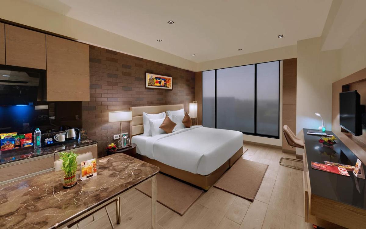 a hotel room with a bed and a television at Wyndham Ahmedabad Shela in Ahmedabad