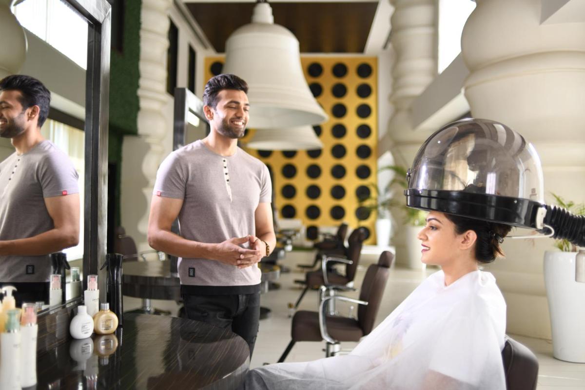 a man standing next to a woman in a hair salon at Wyndham Ahmedabad Shela in Ahmedabad