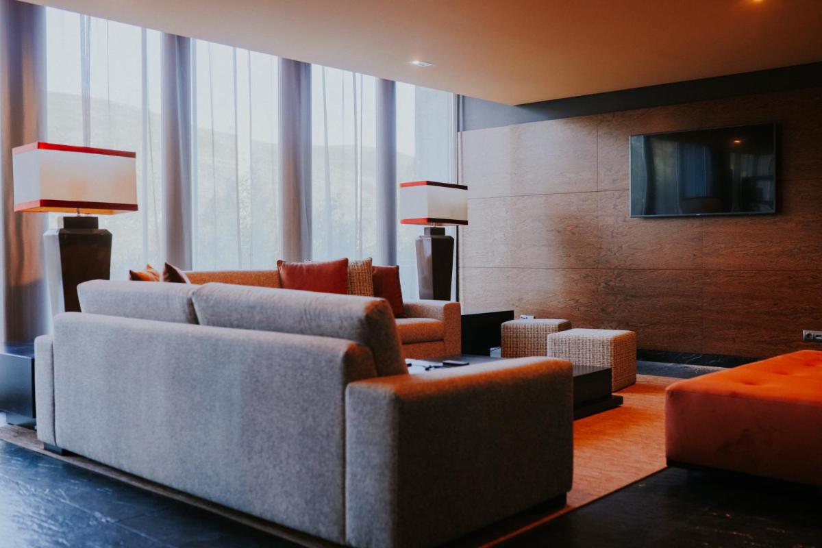 uma sala de estar com sofás, cadeiras e uma televisão em H2otel Congress & Medical SPA em Unhais da Serra