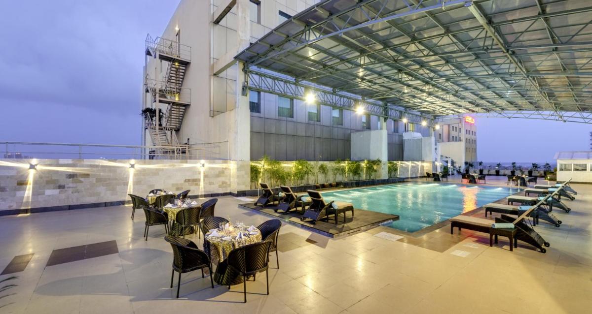 a hotel with a pool and tables and chairs at Pride Plaza Hotel, Kolkata in Kolkata