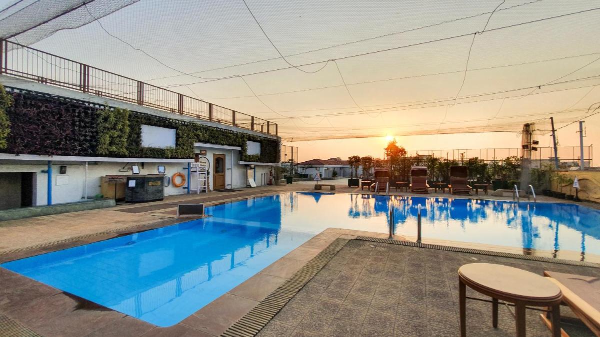 a large swimming pool with a sunset in the background at The Orchid Hotel Mumbai Vile Parle in Mumbai a large swimming pool with a sunset in the background at The Orchid Hotel Mumbai Vile Parle in Mumbai