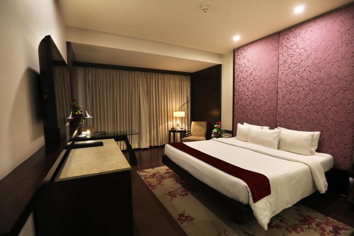 a bedroom with a large bed and a purple wall at Hotel Royal Orchid Jaipur, Tonk Road in Jaipur