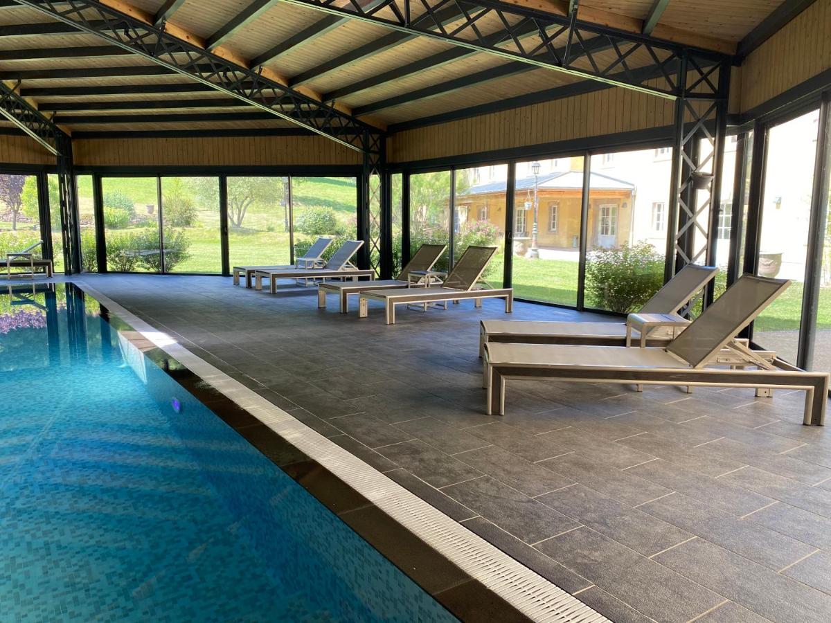 une piscine avec des chaises longues à côté d'un bâtiment dans l'établissement Le 1837, à Saint-Affrique