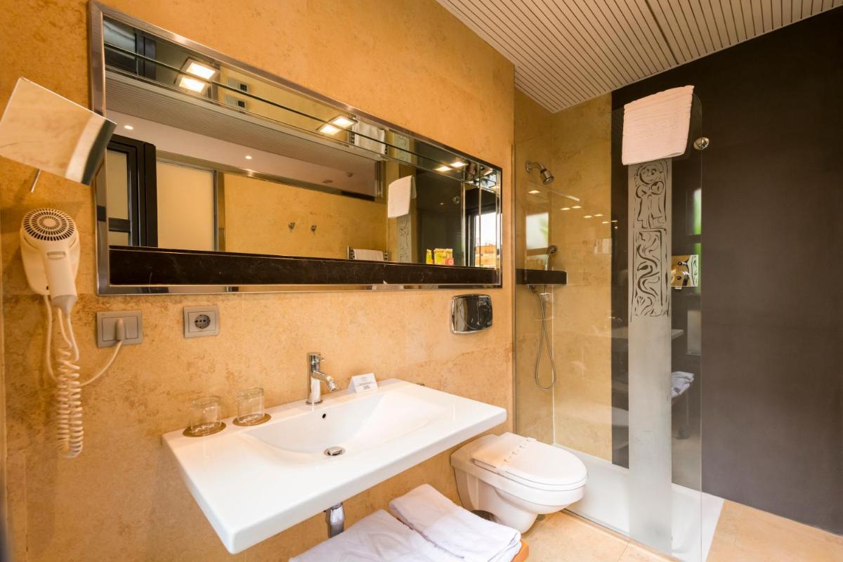 Un baño con lavabo, inodoro y espejo. en Hotel Fruela, en Oviedo