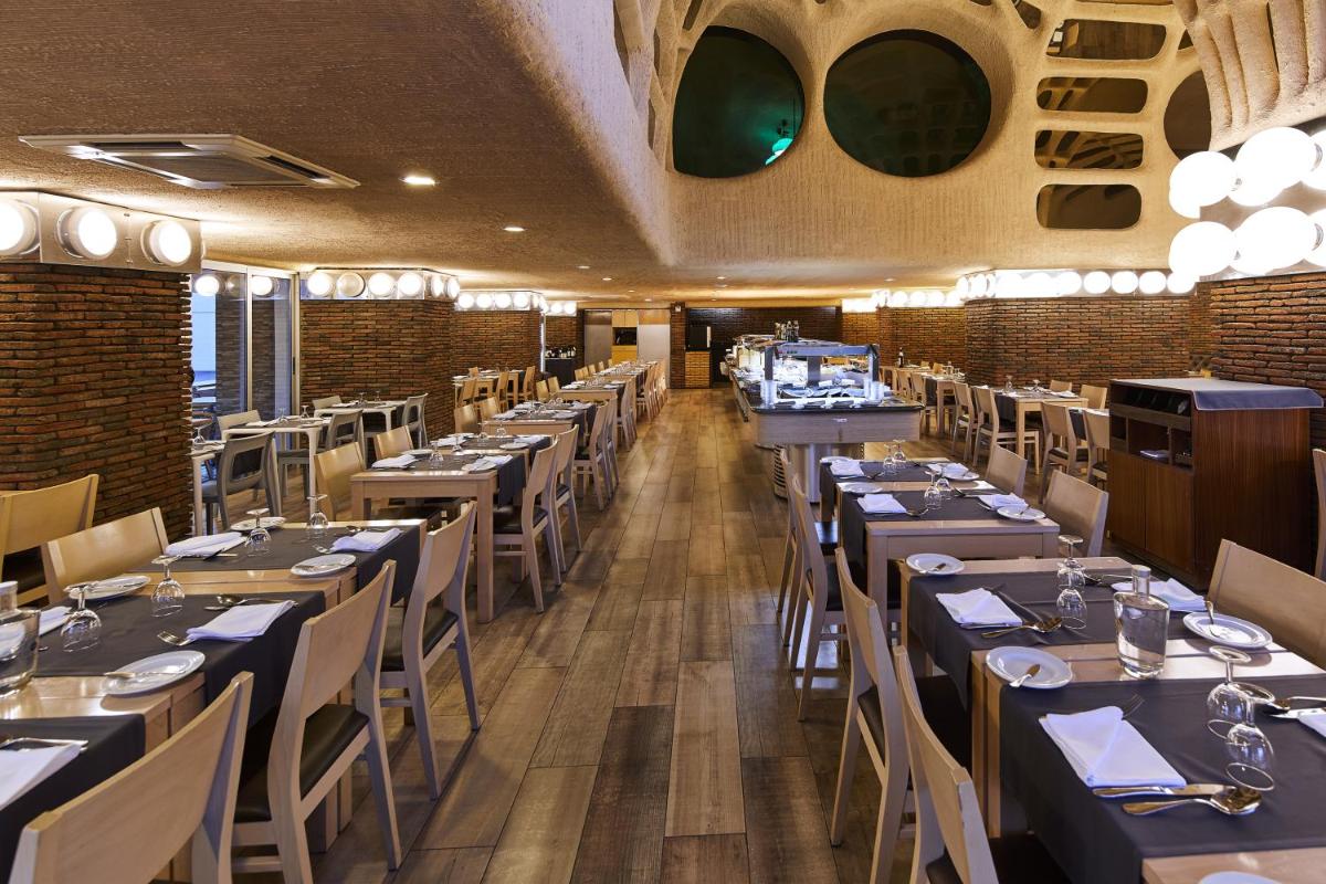 uma sala de jantar com mesas e cadeiras em um restaurante em Alcazar Hotel & SPA em Monte Gordo