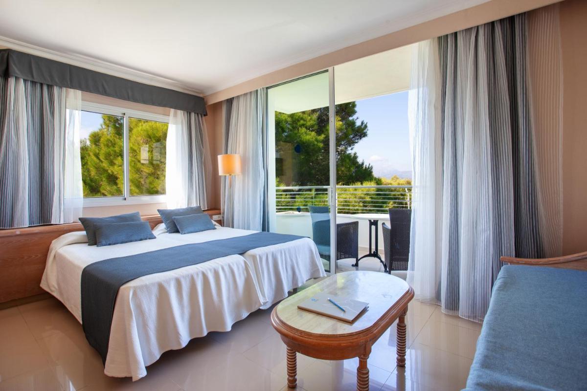 Una habitación de hotel con una cama y una ventana grande. en Grupotel Natura Playa, en Playa de Muro