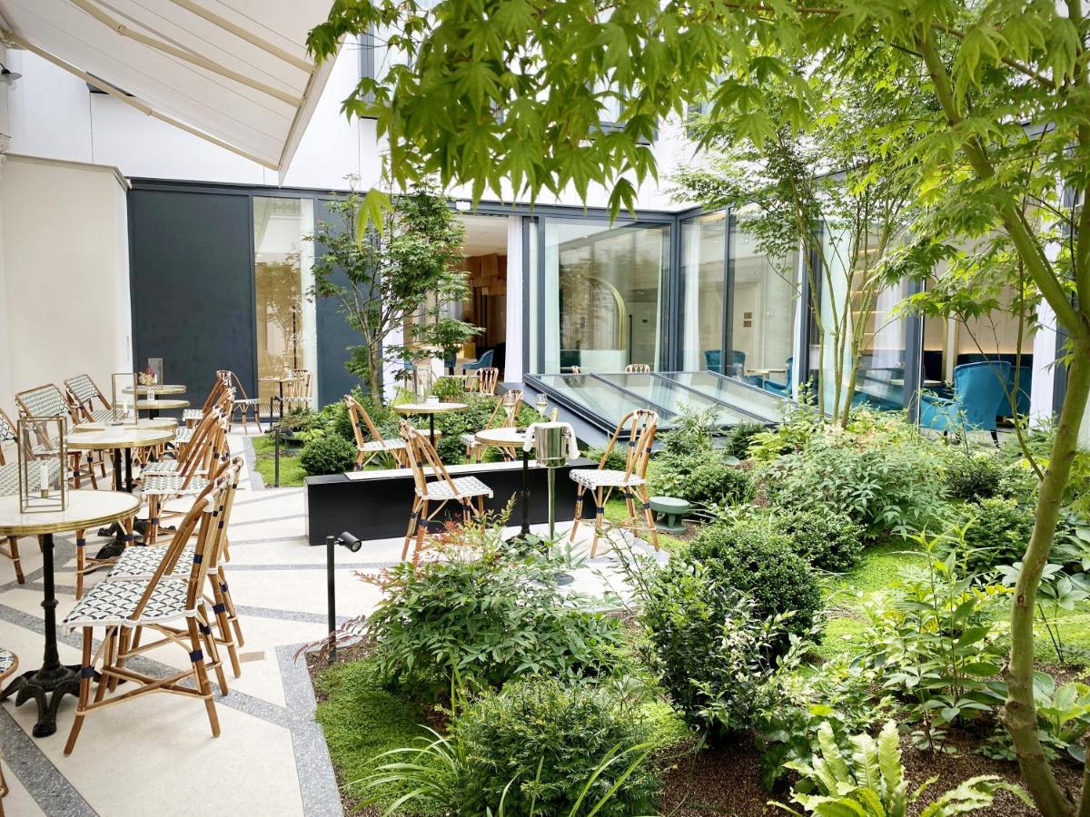 un patio extérieur avec tables, chaises et plantes dans l'établissement Maison Albar - Le Vendome, à Paris