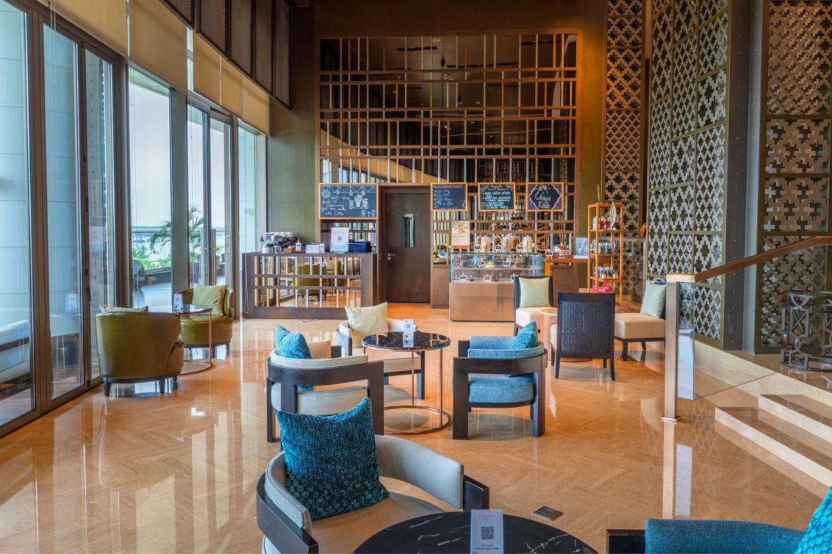 a lobby with tables and chairs and windows at Grand Hyatt Kochi Bolgatty in Cochin