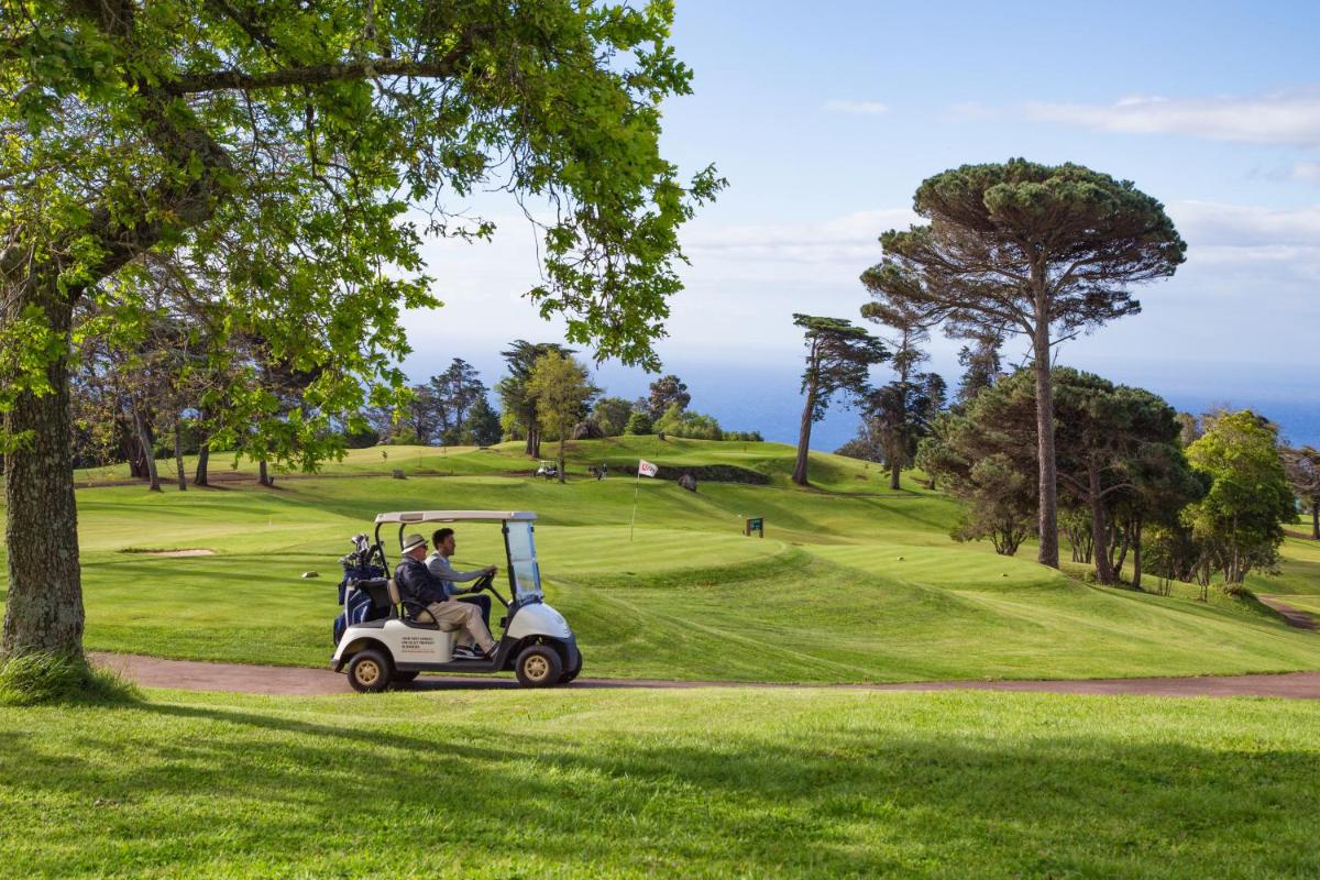 um carrinho de golfe a descer um campo de golfe em Casa Velha do Palheiro Relais & Chateaux no Funchal
