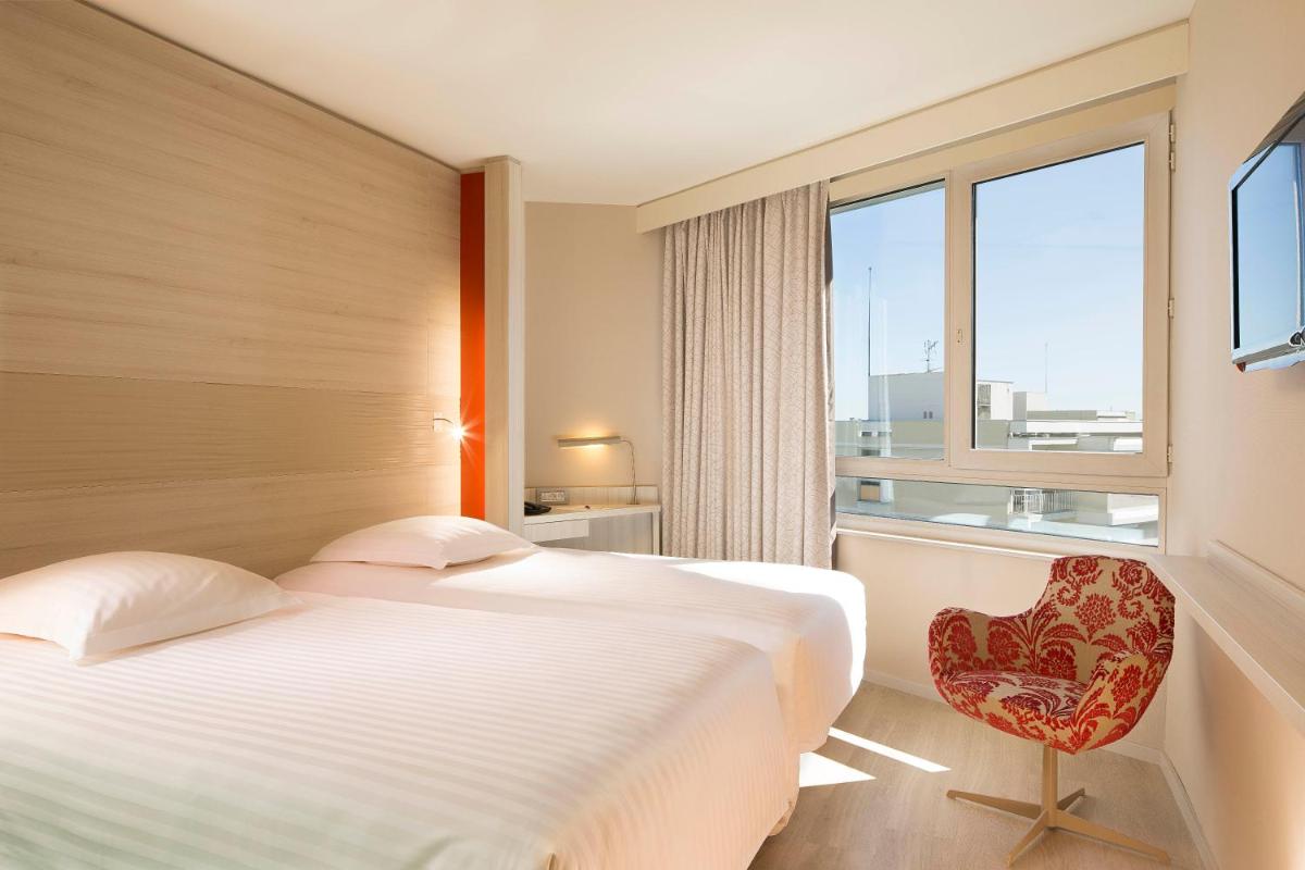 une chambre avec un lit, une chaise et une fenêtre dans l'établissement Oceania Clermont Ferrand, à Clermont-Ferrand