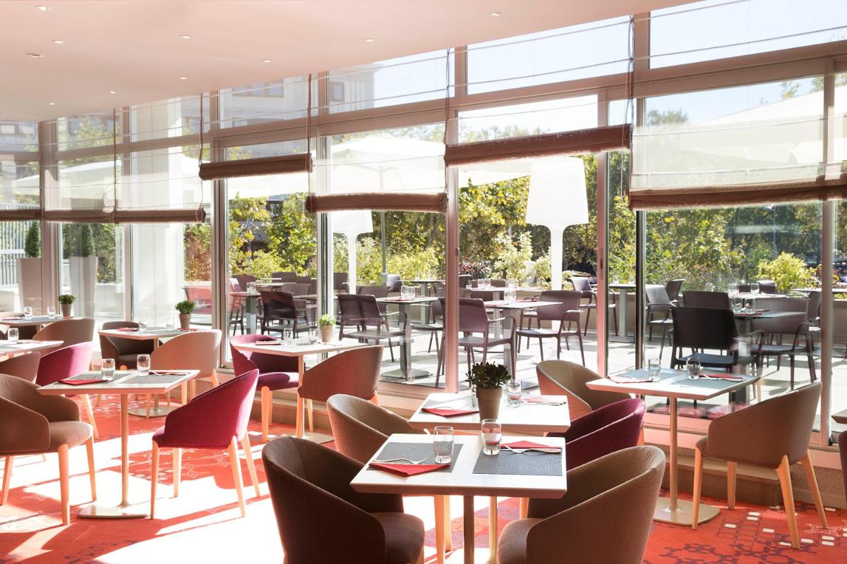 un restaurant avec des tables, des chaises et des fenêtres dans l'établissement Oceania Clermont Ferrand, à Clermont-Ferrand