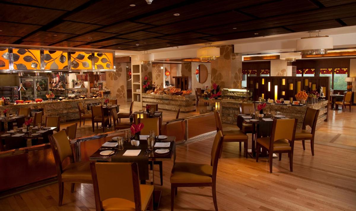 a restaurant with tables and chairs and a bar at Crowne Plaza New Delhi Okhla by IHG in New Delhi