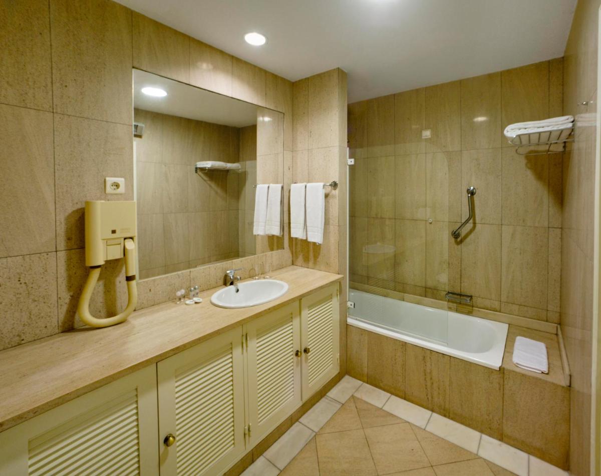 um banheiro com pia e banheira em Cerro Da Marina Hotel - Adults Only em Albufeira