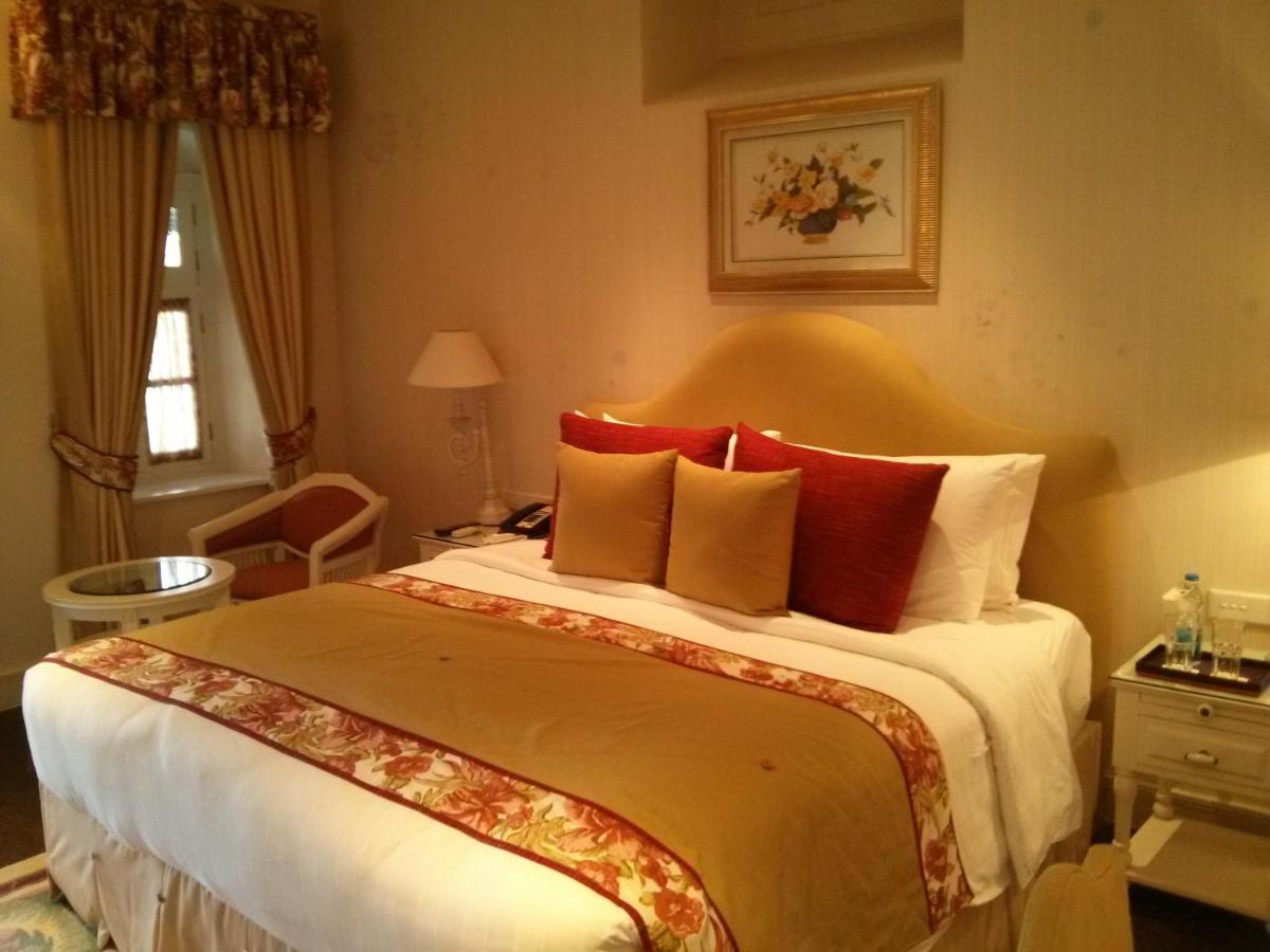 a hotel room with a large bed with red pillows at Welcomhotel by ITC Hotels, The Savoy, Mussoorie in Mussoorie