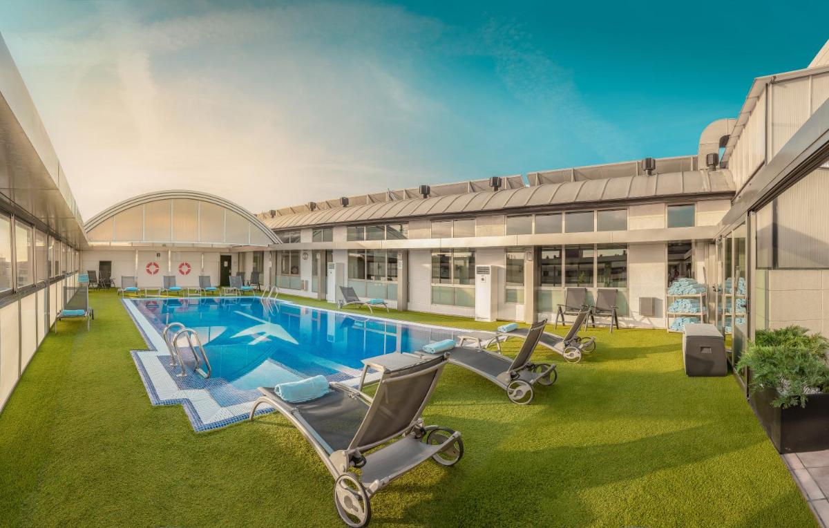 Una piscina con tumbonas frente a un edificio. en SH Valencia Palace, en Valencia