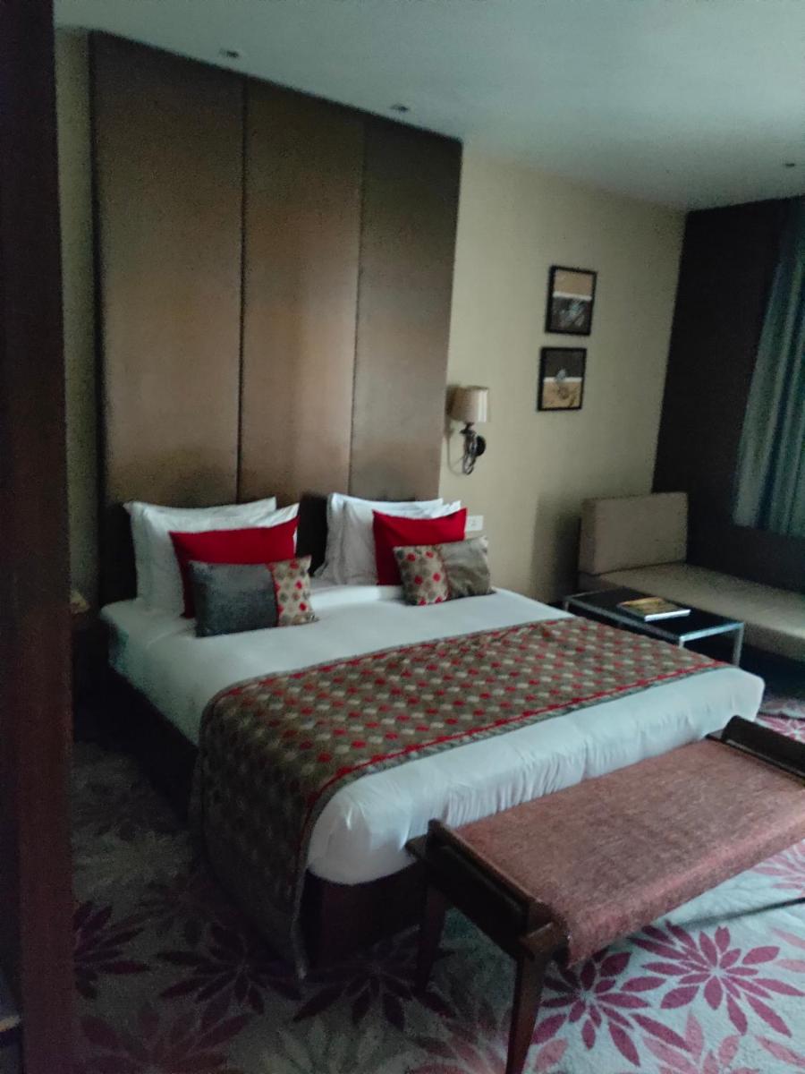 a hotel room with two beds and a couch at Pride Plaza Hotel, Kolkata in Kolkata