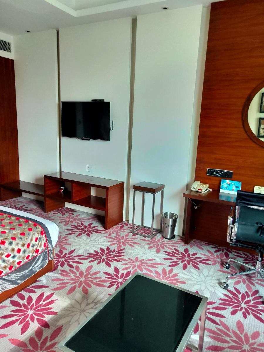 a hotel room with a bed and a flat screen tv at Pride Plaza Hotel, Kolkata in Kolkata