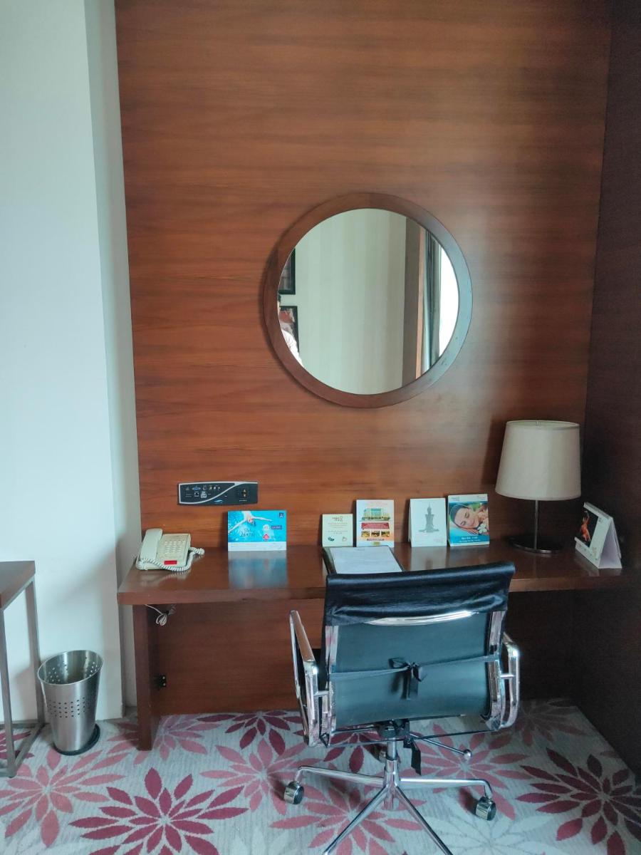 a desk with a chair in a room with a mirror at Pride Plaza Hotel, Kolkata in Kolkata