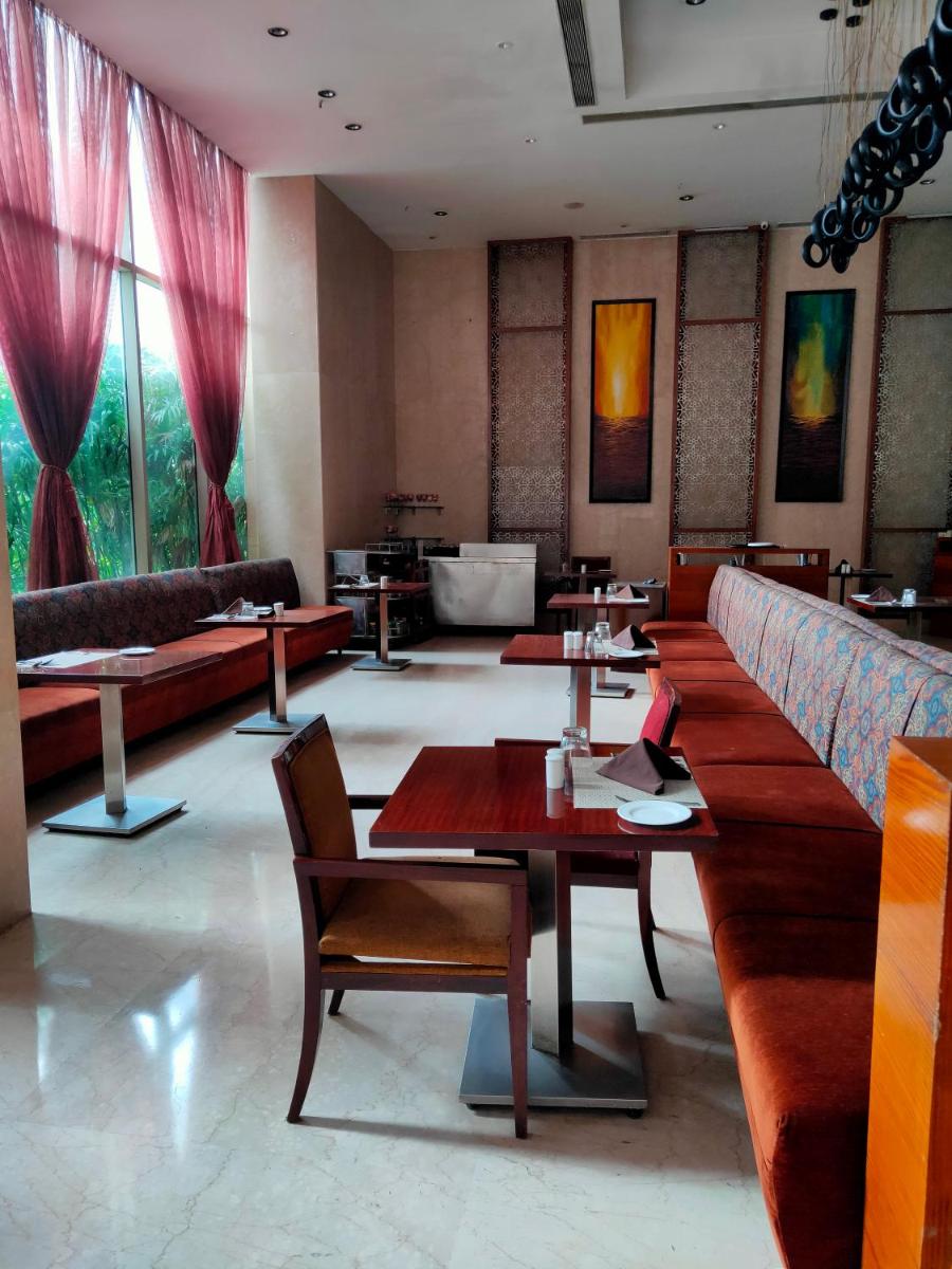 a restaurant with tables and couches in a room at Pride Plaza Hotel, Kolkata in Kolkata