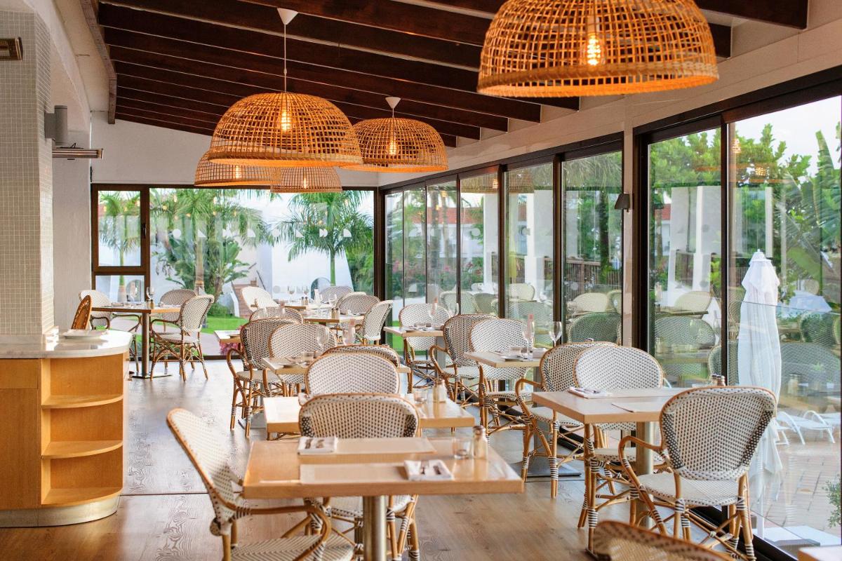 Un restaurante con mesas, sillas y ventanas. en Sunprime Atlantic View Suite & Spa, en Playa del Inglés