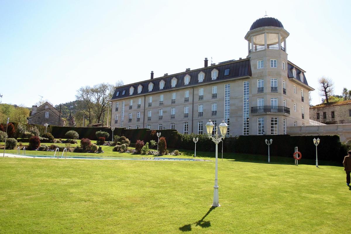 un gran edificio con una torre de reloj sobre un césped en Balneario de Mondariz, en Mondariz-Balneario