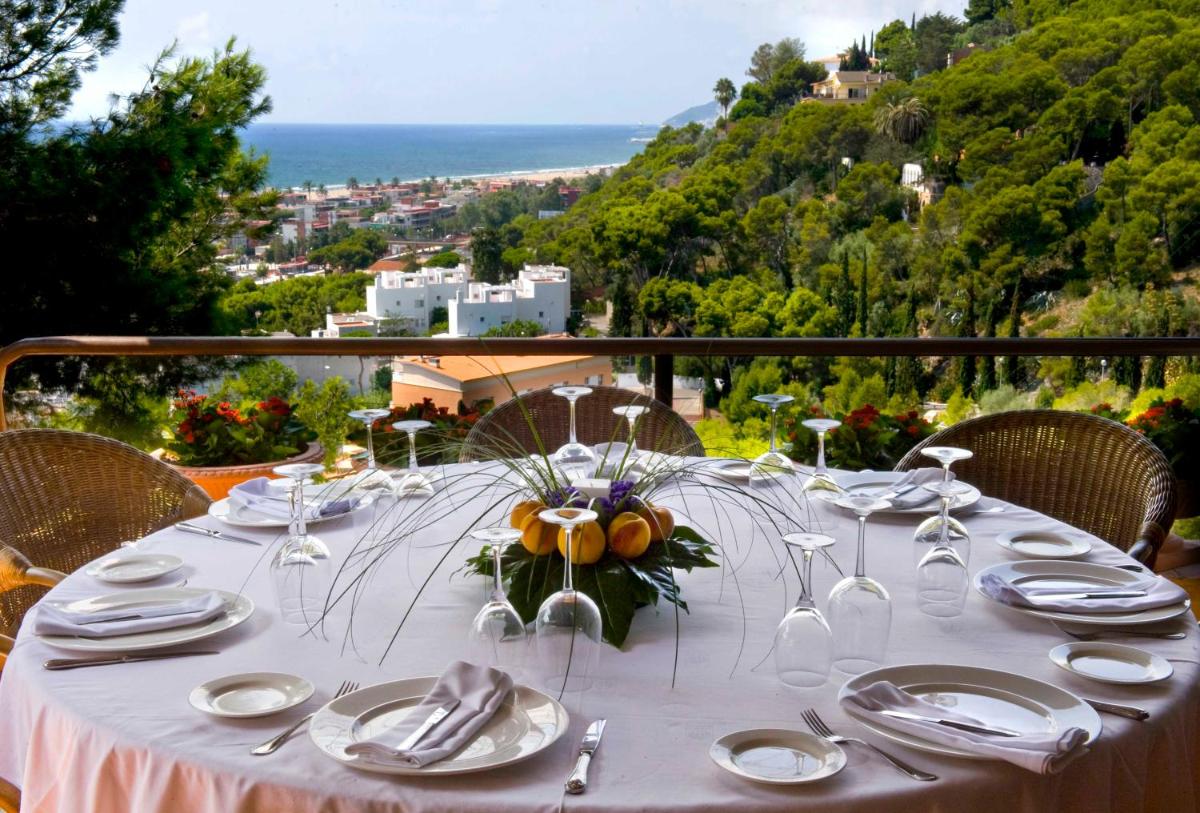una mesa con platos y copas de vino y vistas al océano en Gran Hotel Rey Don Jaime, en Castelldefels