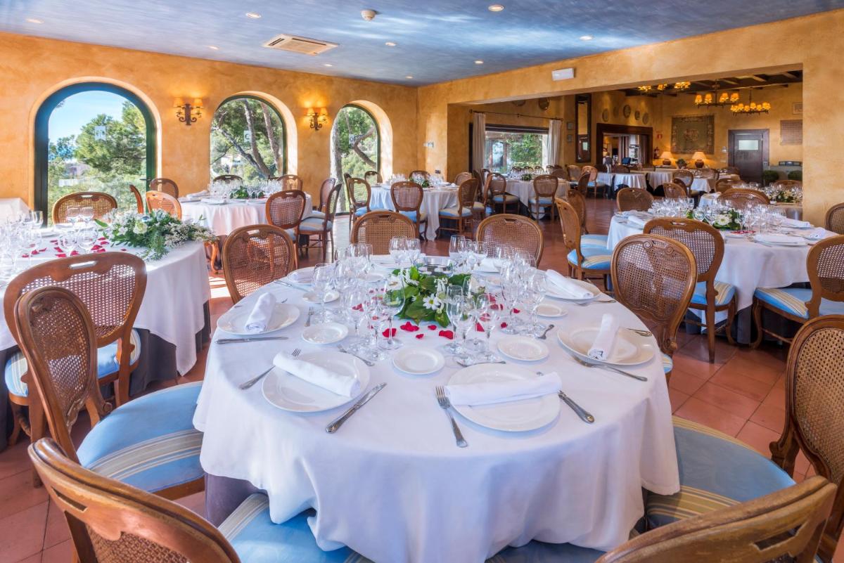 Un comedor con mesas y sillas blancas. en Gran Hotel Rey Don Jaime, en Castelldefels