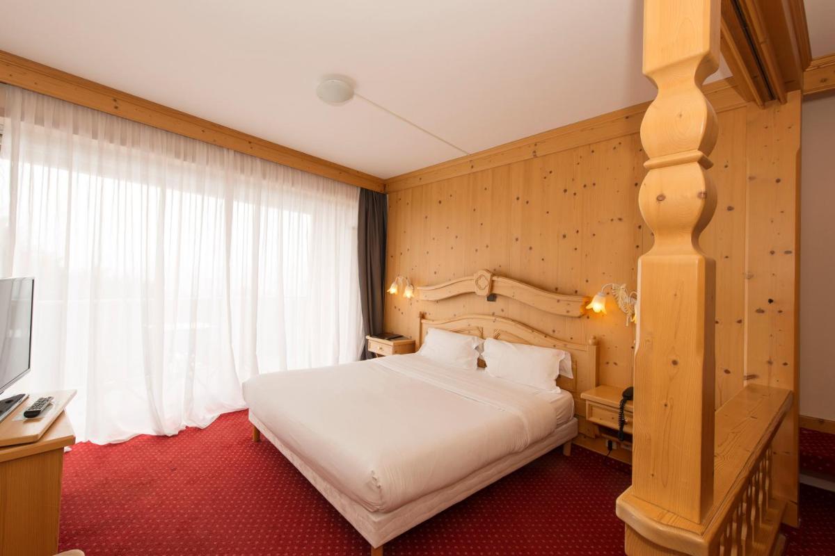 une chambre avec un grand lit blanc et une fenêtre dans l'établissement Alexain Hotel Restaurant & Wellness - Colmar Ouest, à Trois-Épis 74 autres photos