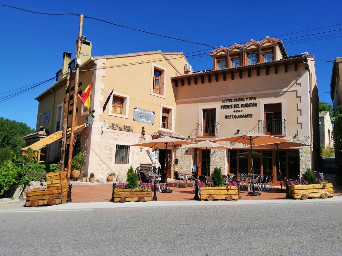 un edificio con mesas y sombrillas en una calle en Hotel Rural & SPA Puente del Duratón, en Sepúlveda