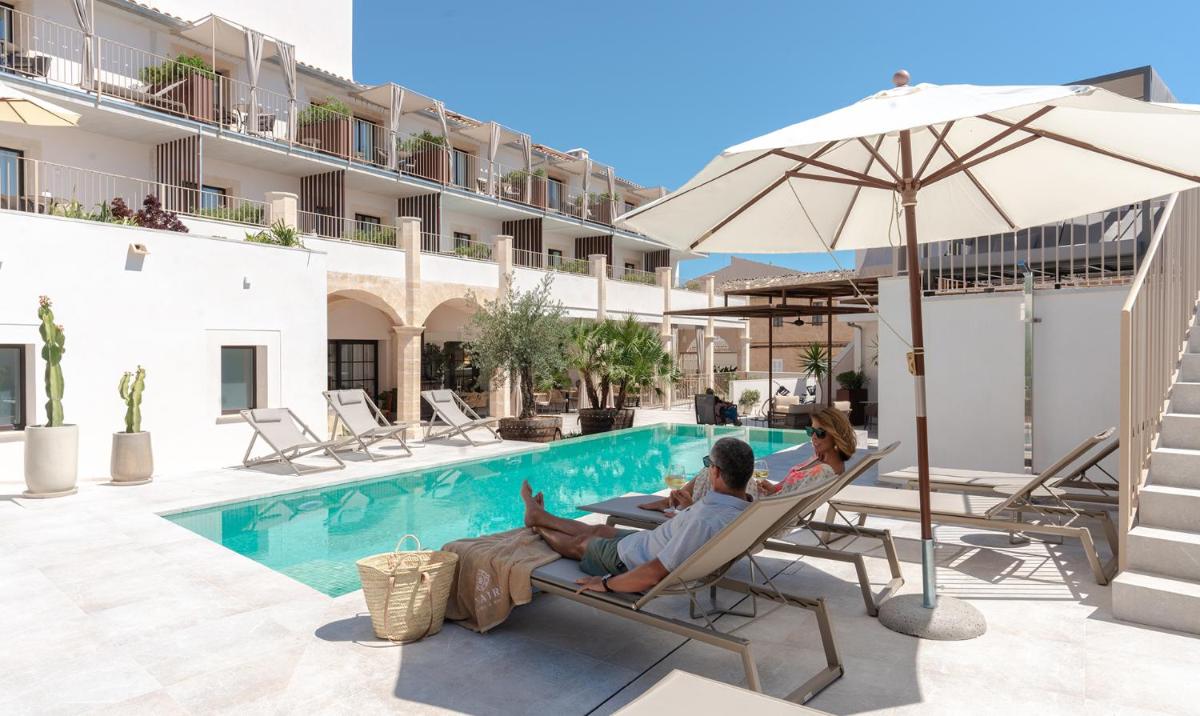 un hombre y una mujer sentados en sillas junto a una piscina en Ynaira hotel & Spa, en Ariany