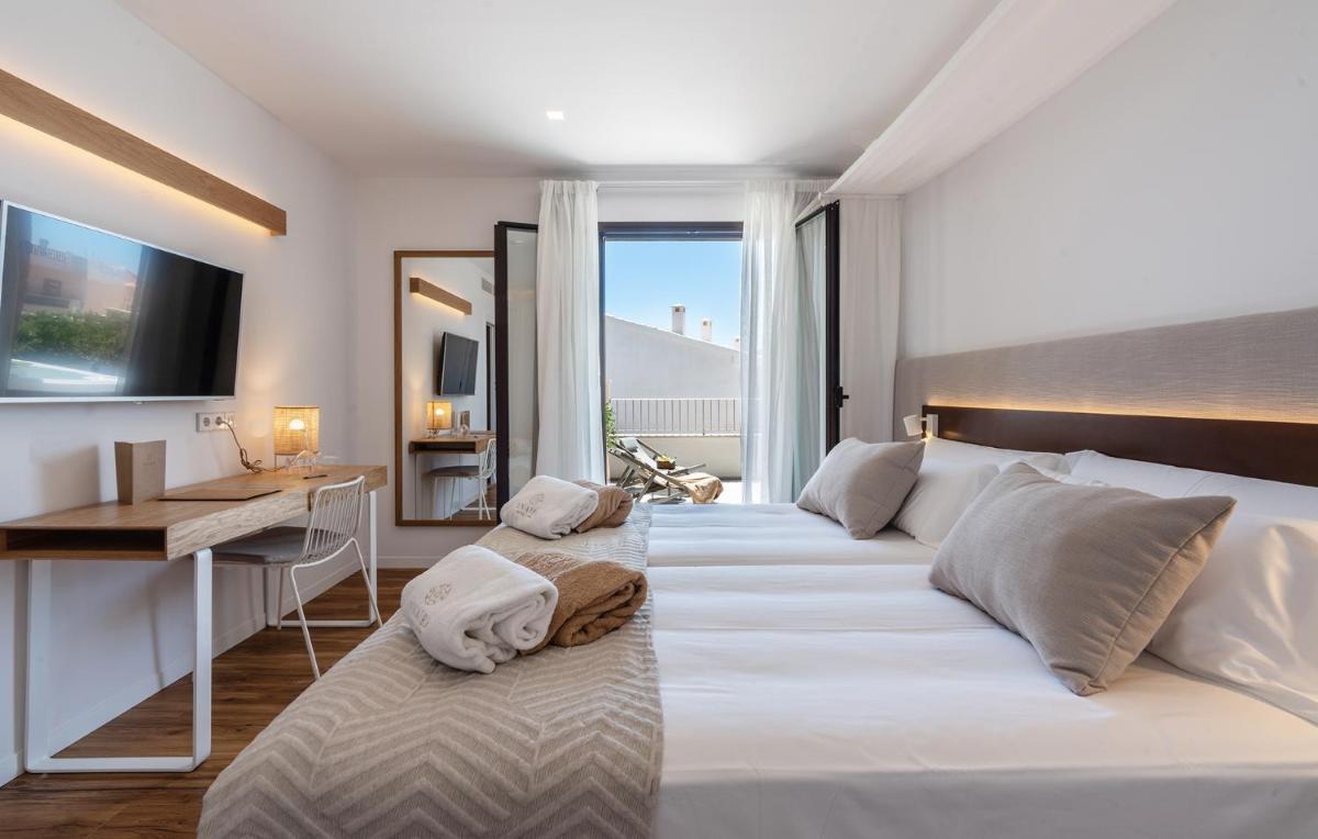 Un dormitorio con dos camas y un escritorio y una ventana. en Ynaira hotel & Spa, en Ariany 114 fotos más