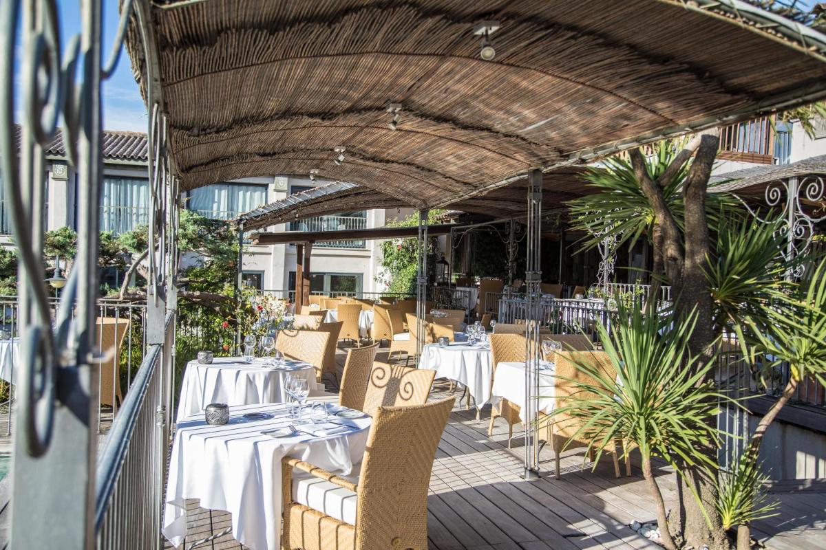 un restaurant avec des tables et des chaises blanches sur une terrasse dans l'établissement Hôtel Le Roi Théodore & Spa, à Porto-Vecchio