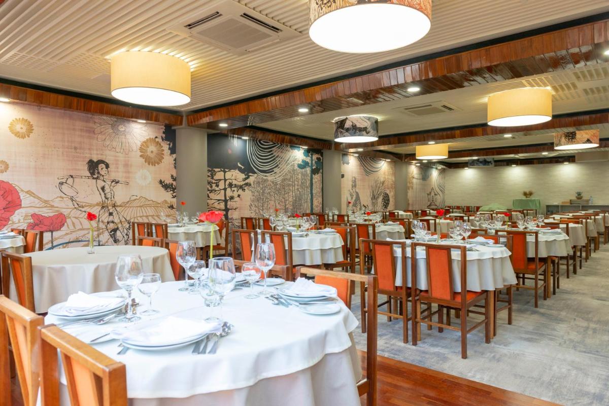 uma sala de jantar com mesas e cadeiras brancas em D. Afonso Hotel & SPA em Monte Real