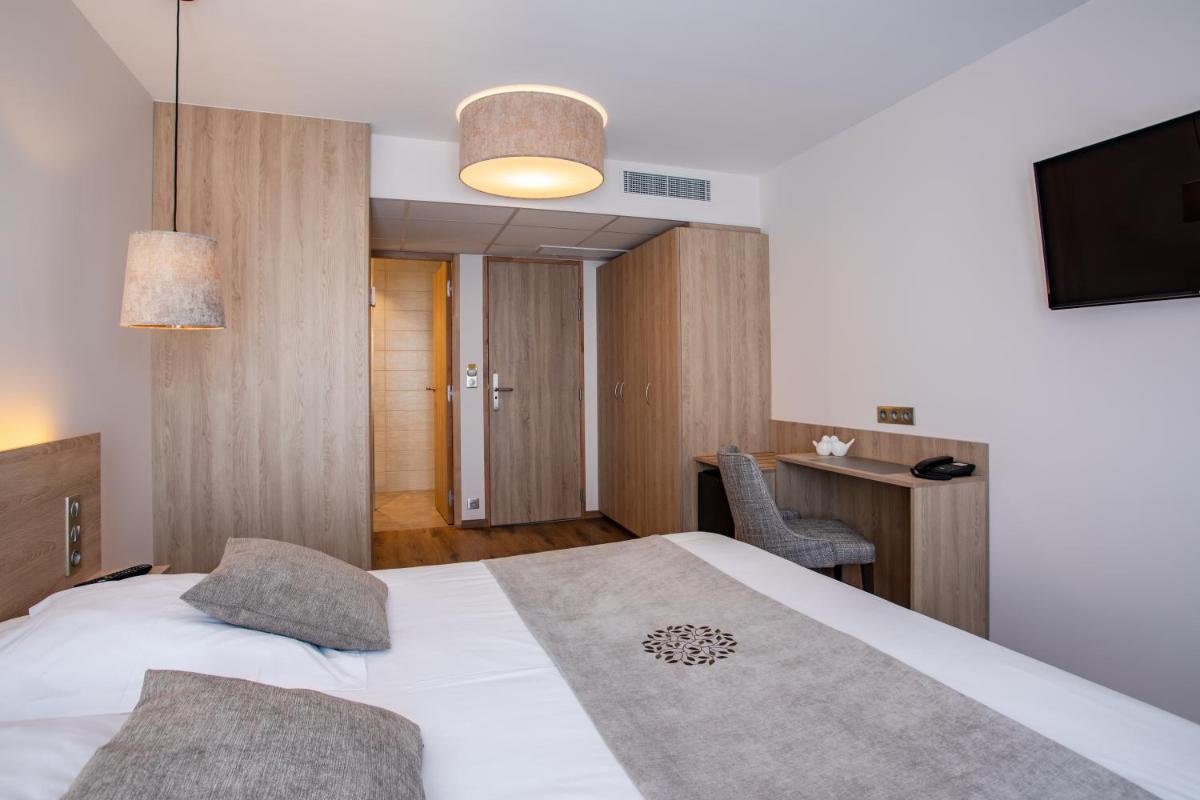 une chambre avec un lit, un bureau et une télévision dans l'établissement Hôtel SPA du Lac de Madine - Maison DRAPIER, à Heudicourt-sous-les-Côtes