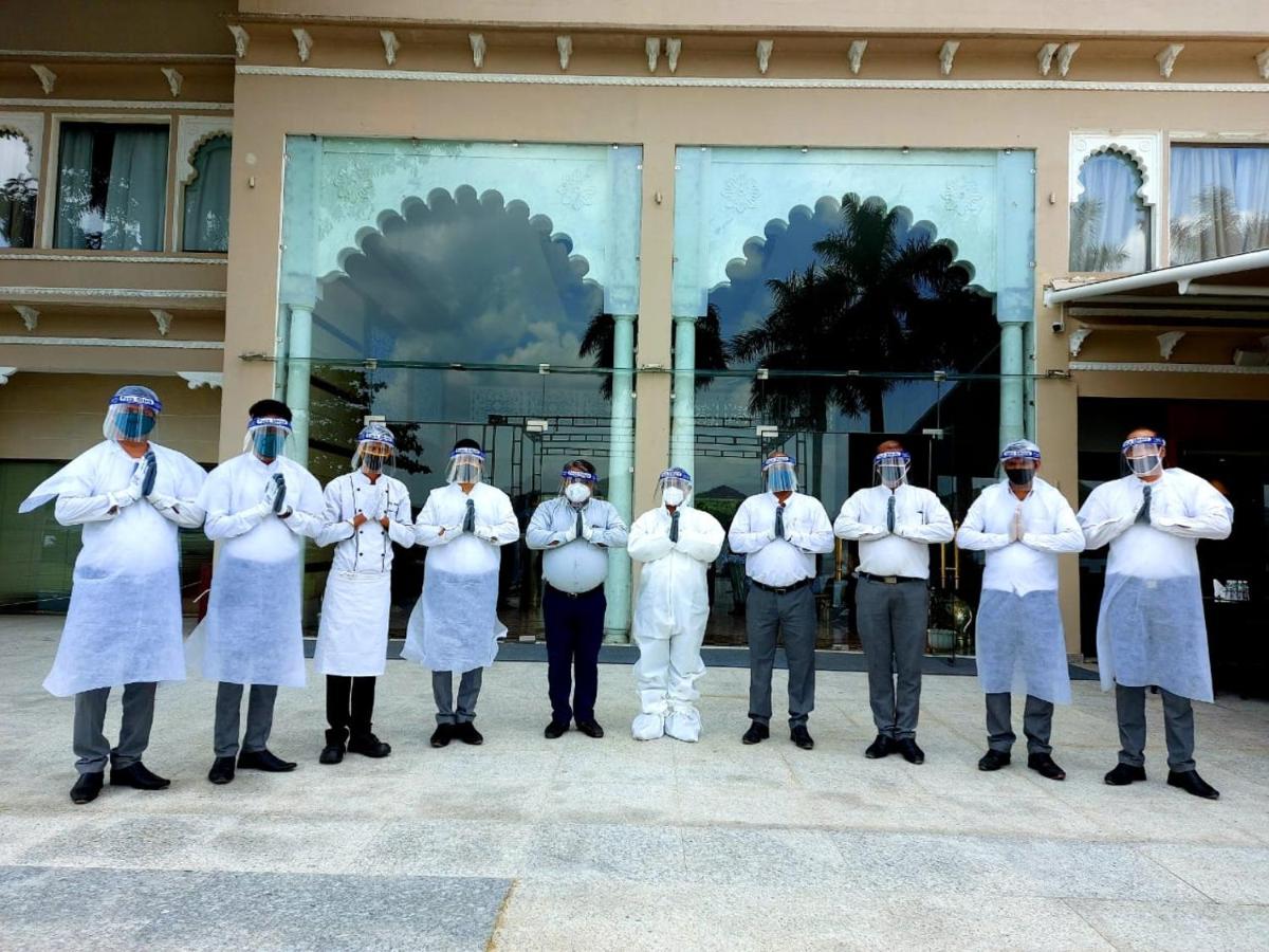 a group of people in white uniforms standing in front of a building at Hotel Lakend in Udaipur