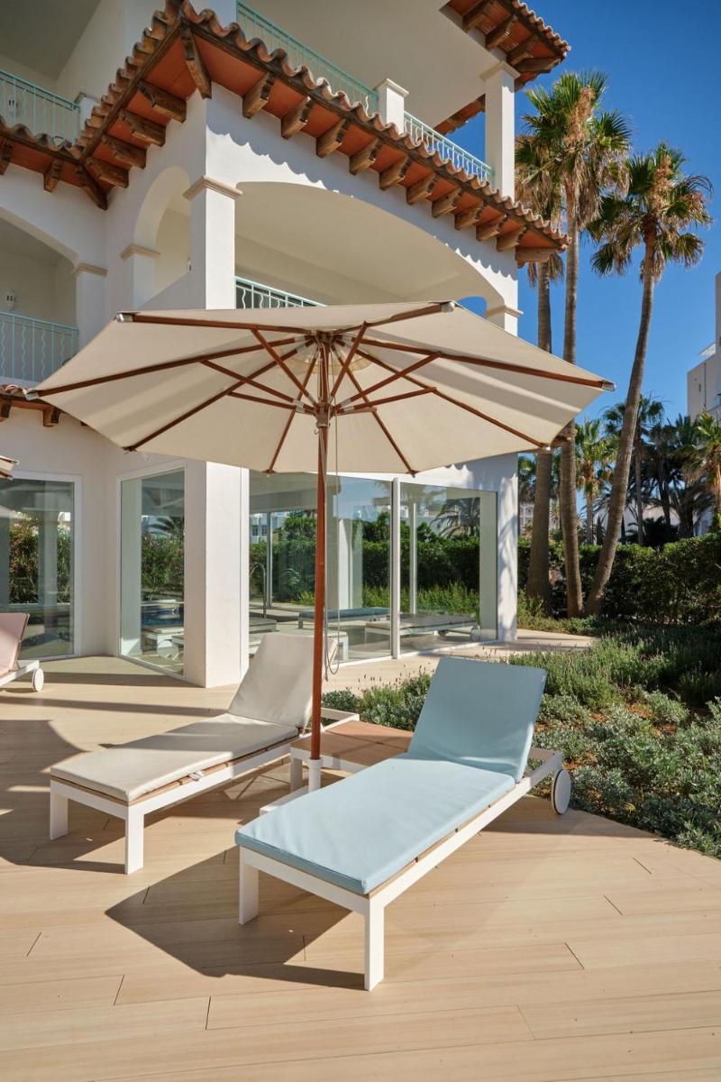 un patio con 2 tumbonas y una sombrilla en Hotel Villa Chiquita - Adults Only - Over 12, en Colonia de Sant Jordi