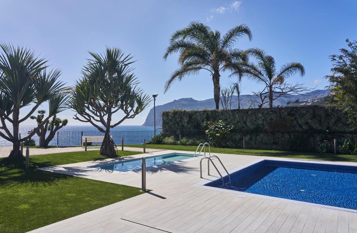 uma piscina com palmeiras e o oceano em Golden Residence Hotel no Funchal