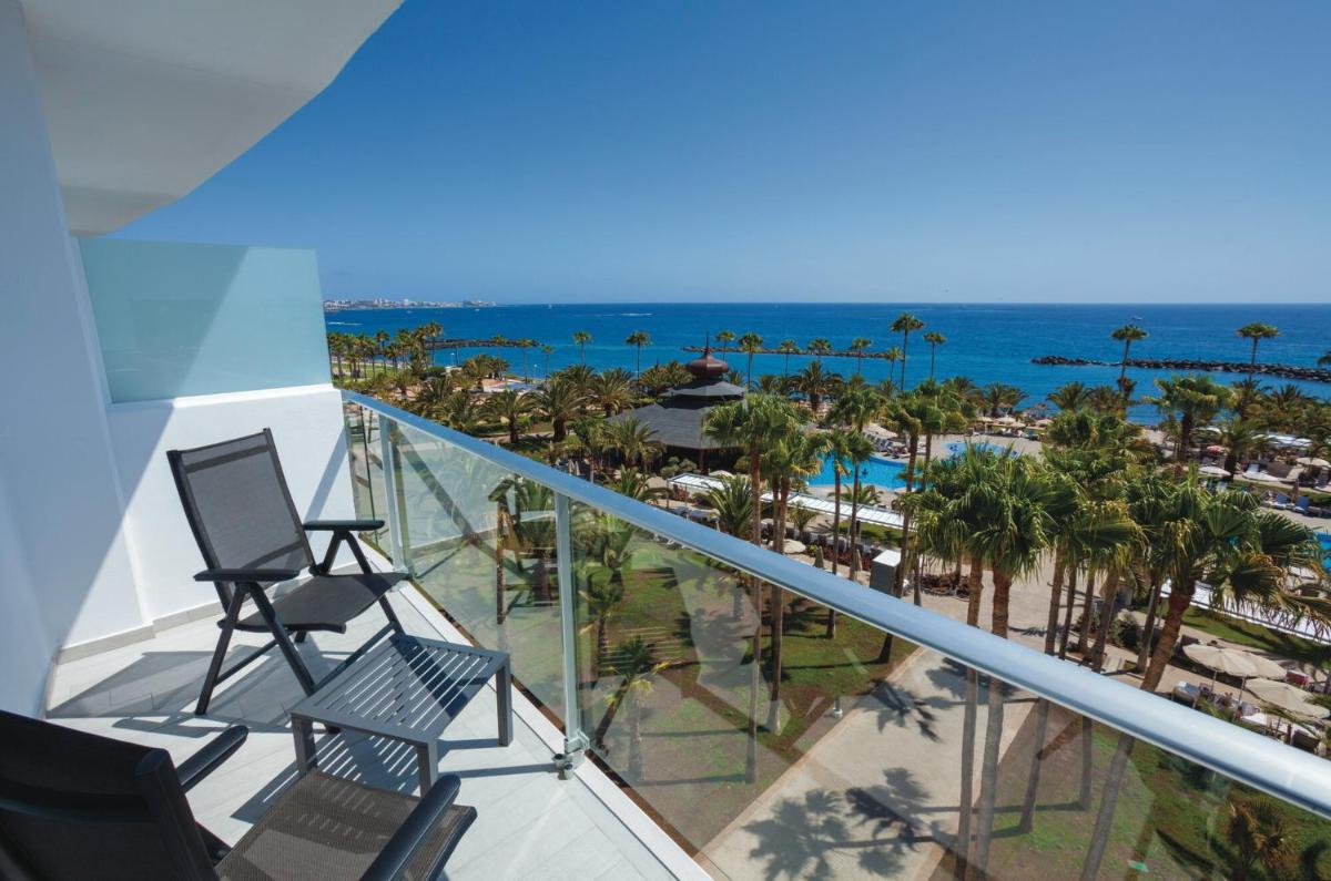 Un balcón con sillas y vista a la playa. en Hotel Riu Palace Tenerife, en Adeje