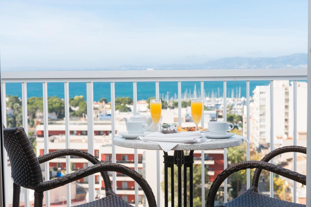 Una mesa con dos vasos de jugo de naranja en un balcón. en Hotel Torre Azul & Spa - Adults Only, en El Arenal