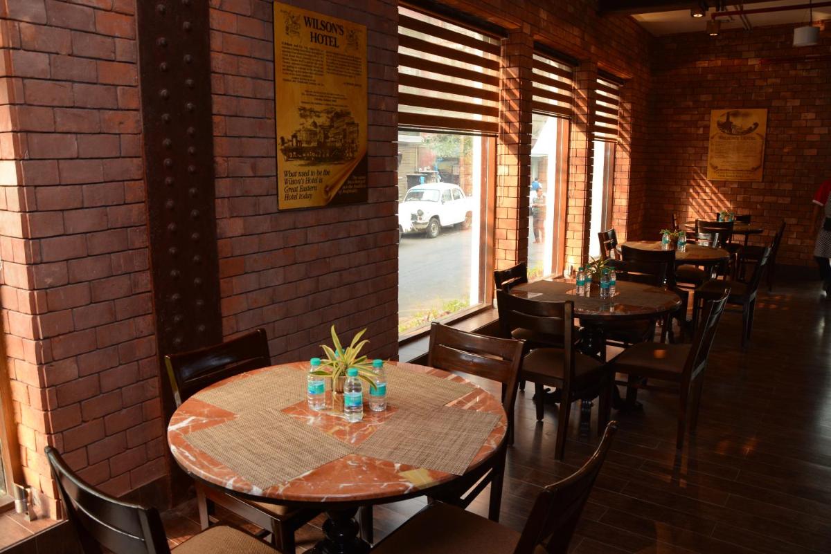 a restaurant with tables and chairs and a brick wall at The Lalit Great Eastern Kolkata in Kolkata a restaurant with tables and chairs and a brick wall at The Lalit Great Eastern Kolkata in Kolkata