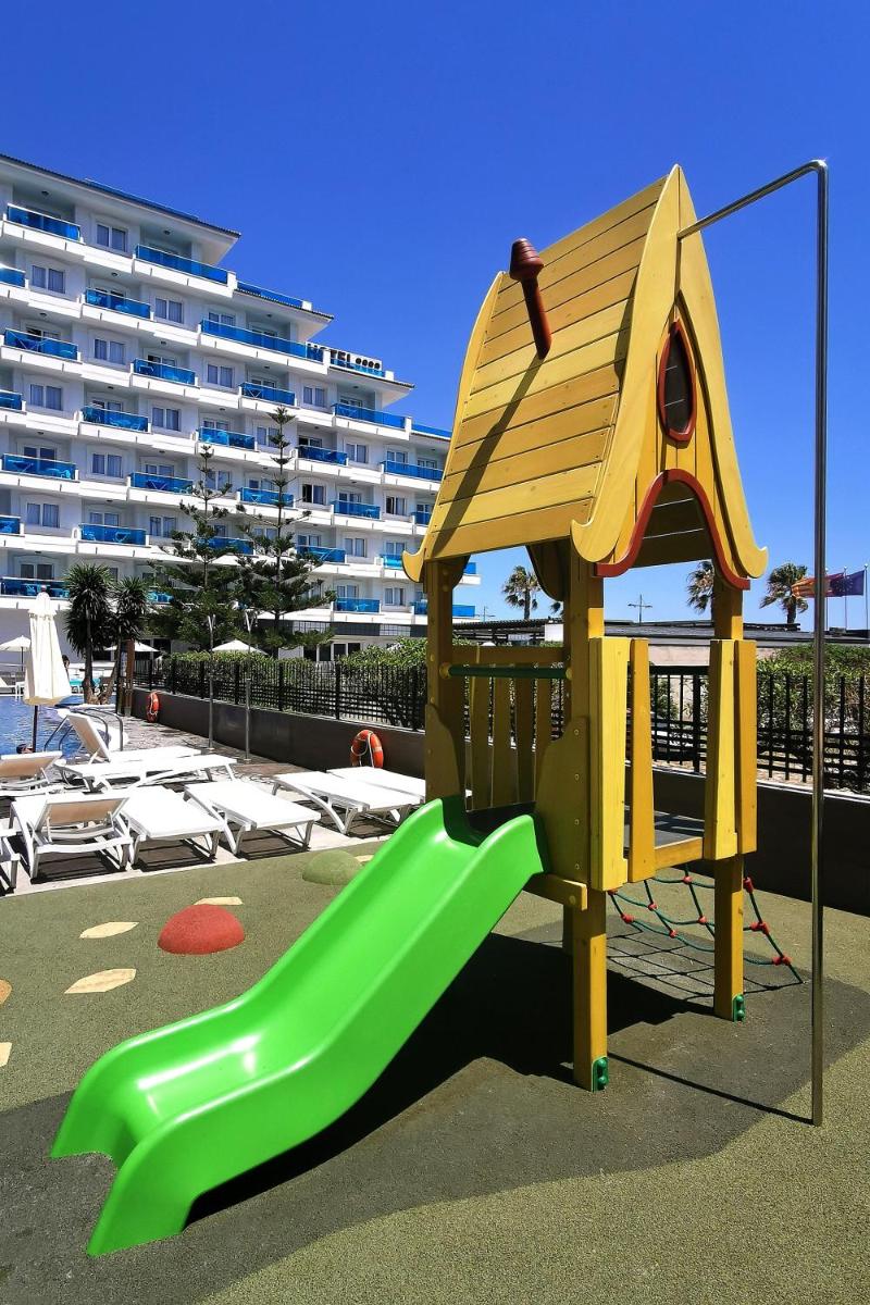 Un parque infantil con un tobogán frente a un edificio. en Aparthotel Acuazul, en Peñíscola