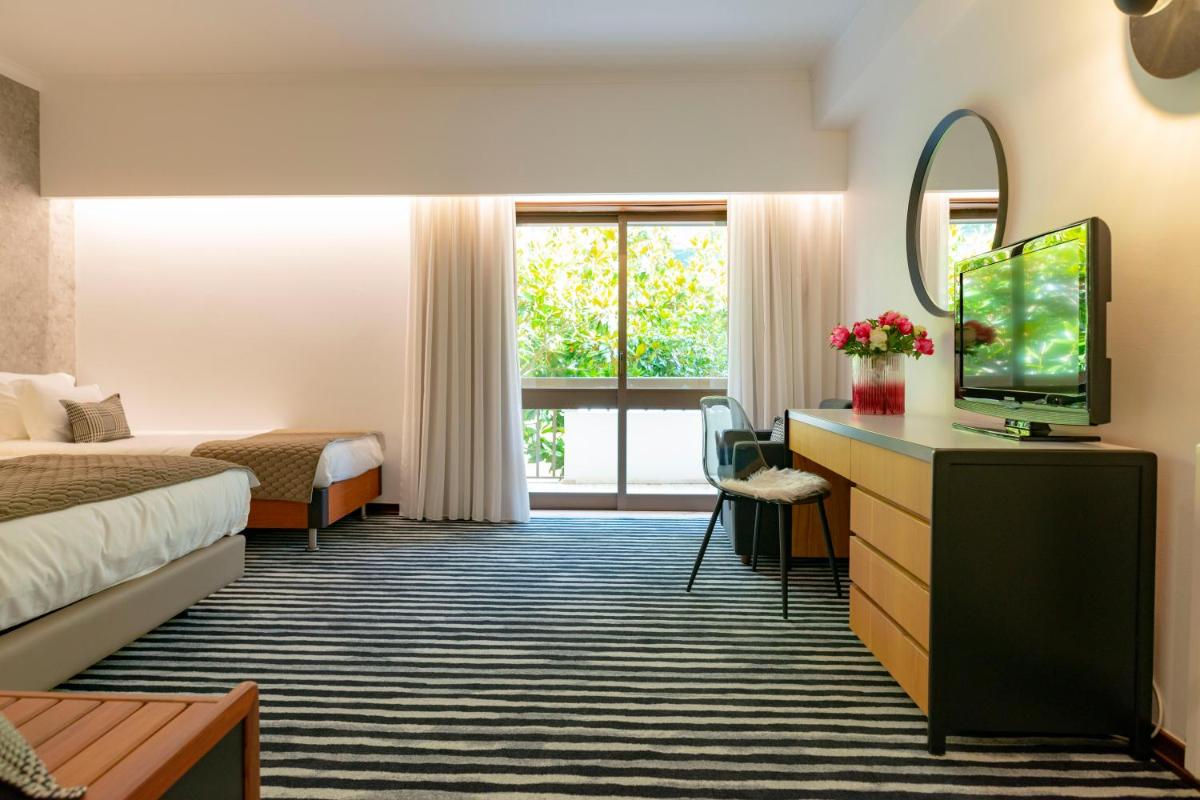 um quarto de hotel com uma cama e uma televisão em D. Afonso Hotel & SPA em Monte Real mais 49 fotografias