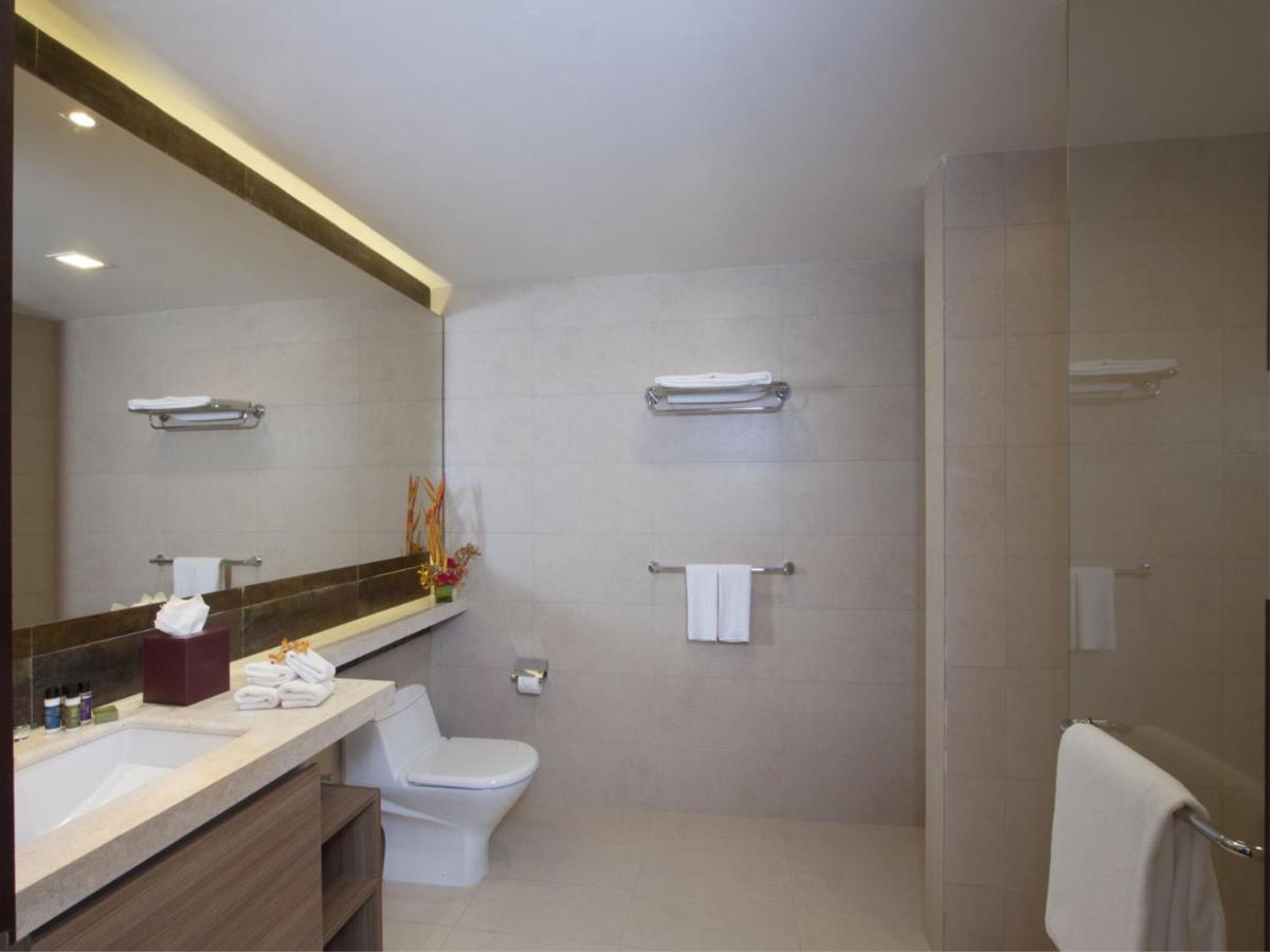 a bathroom with a toilet and a sink and a mirror at Oakwood Residence Whitefield Bangalore in Bengaluru a bathroom with a toilet and a sink and a mirror at Oakwood Residence Whitefield Bangalore in Bengaluru