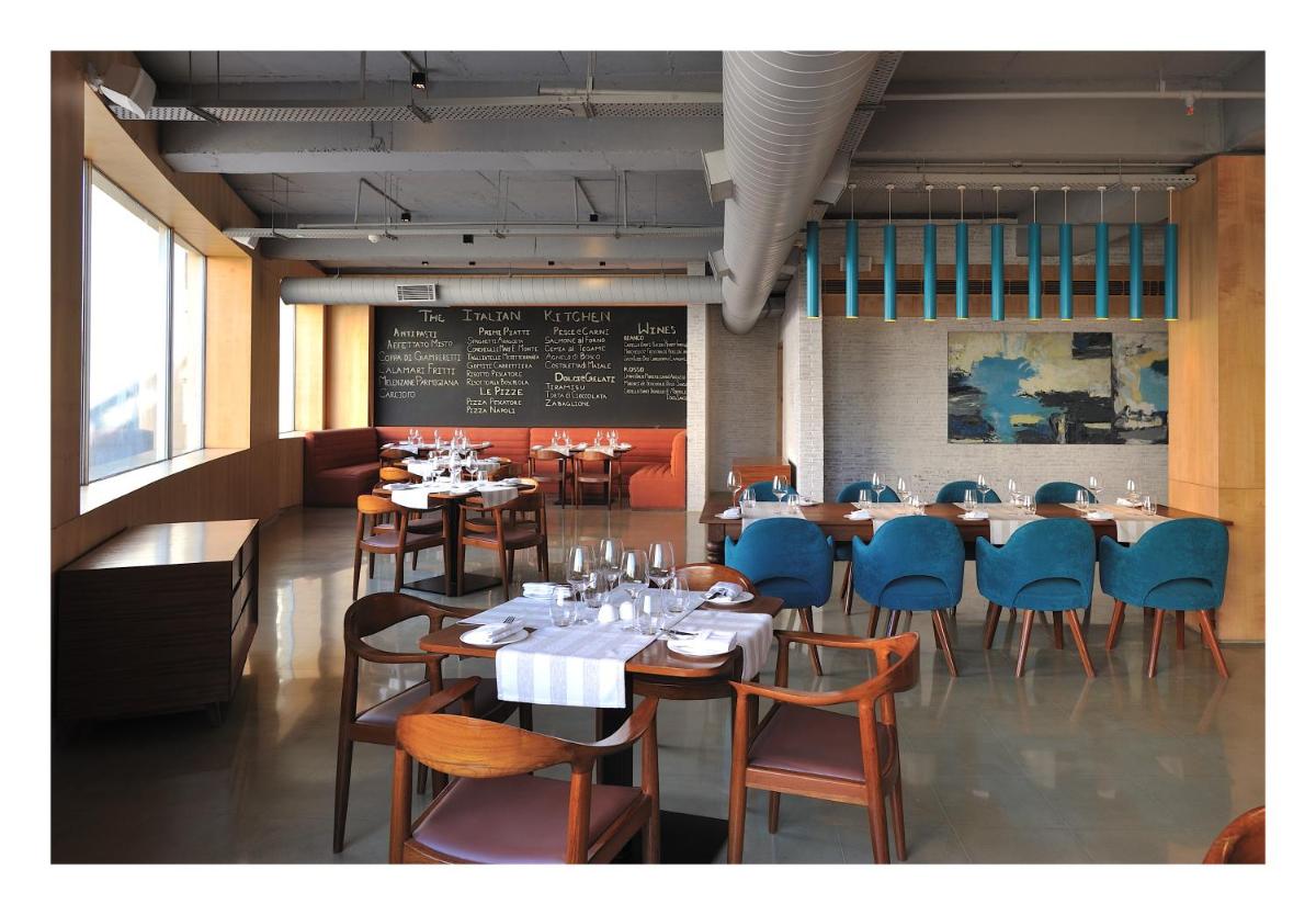 a dining room with tables and chairs and a chalkboard at The Anya Hotel-Golf Course Road in Gurgaon
