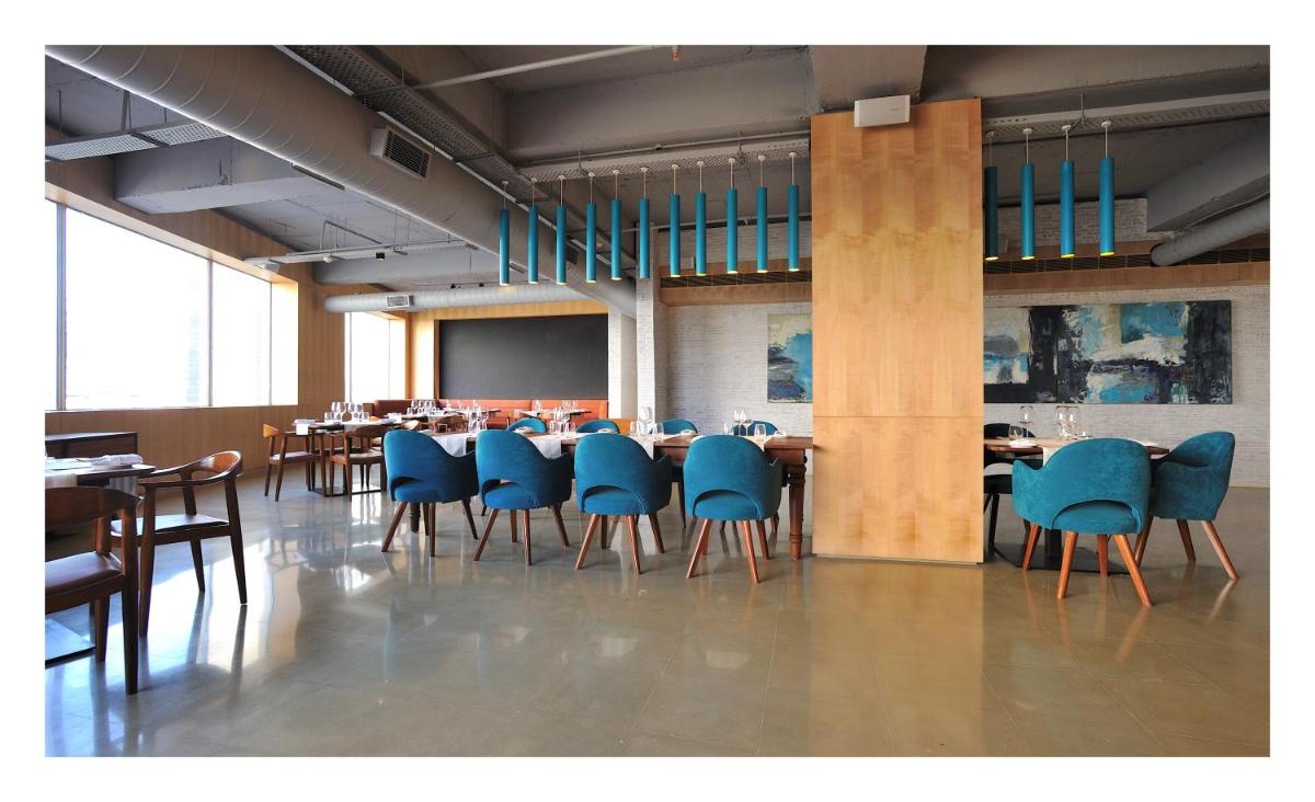 a dining room with tables and blue chairs at The Anya Hotel-Golf Course Road in Gurgaon