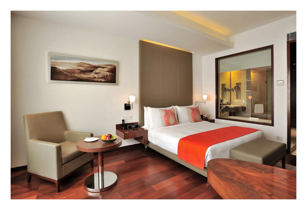 a hotel room with a bed and a chair at The Anya Hotel-Golf Course Road in Gurgaon