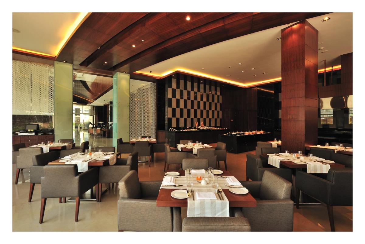 a dining room with tables and chairs in a restaurant at The Anya Hotel-Golf Course Road in Gurgaon